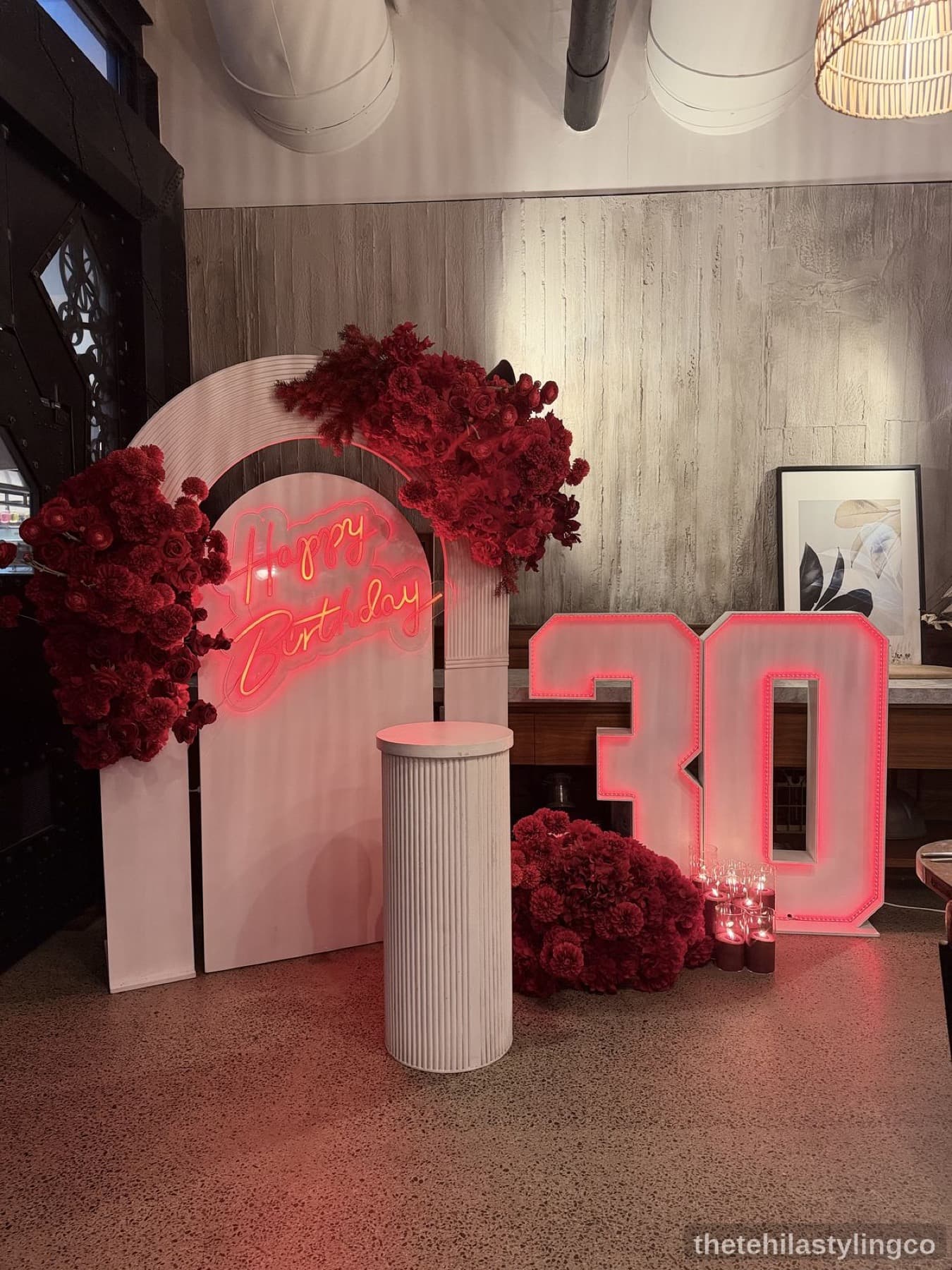 Luxury birthday backdrop with red florals, neon, and marquee lighting
